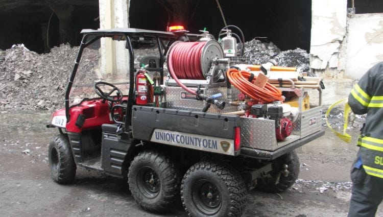 Firefighting UTV in front of partially demolished building.